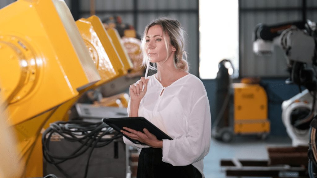 female chief engineer in modern industrial factory with robot arms talking and planning optimization of production.