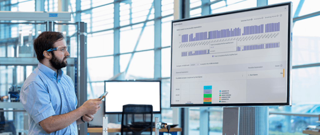 A person standing before a big screen, possibly giving a presentation or attending a conference.