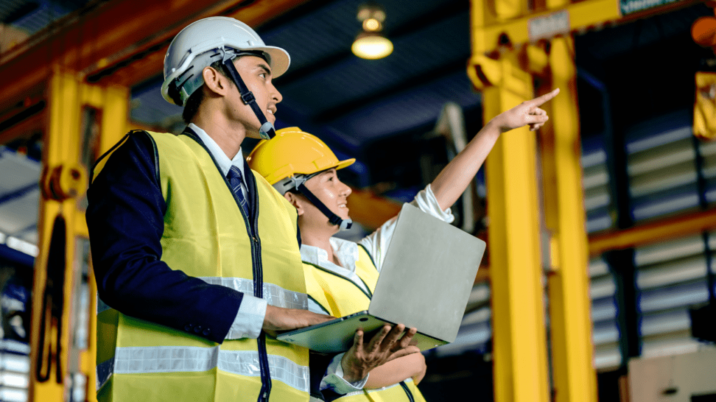 Engineers wearing hardhat and holding checklist standing at machine area