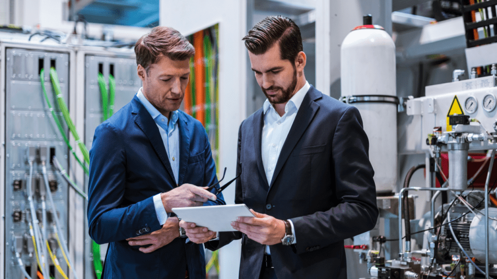 Two businessmen in factory looking at tablet