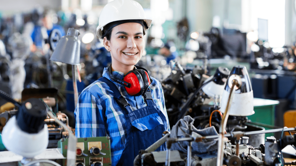 Portrait of industrial engineer facing the camera standing in between manufacturing machinery for data analytics