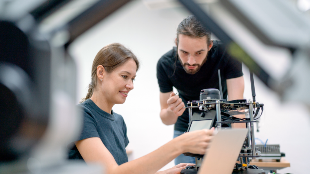 Two Caucasian professional technicians or engineers sit at the workplace and help check - careers in advanced manufacturing