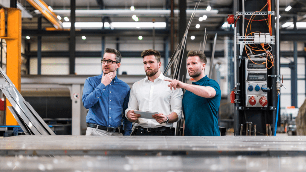 Three men sharing tablet on factory shop floor